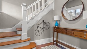 Una escalera con barandas blancas, un pasamanos de madera y piso de madera.