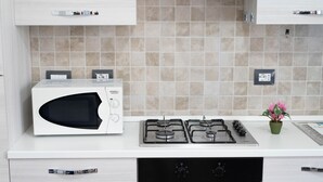 Une cuisine équipée d’un four à micro-ondes, d’une cuisinière, d’un four et agrémentée d’une petite plante en pot.