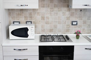 Una cocina con microondas, estufa, horno y una pequeña planta en maceta.