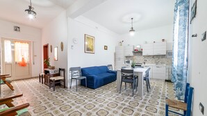 Un espace de vie compact comprenant un coin repas, une kitchenette et un canapé bleu.
