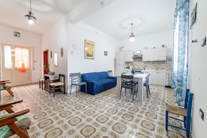 Un espacio habitable pequeño con comedor, kitchenette y un sofá azul.