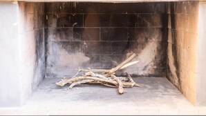 Une cheminée avec une pile de bûches à l’intérieur.