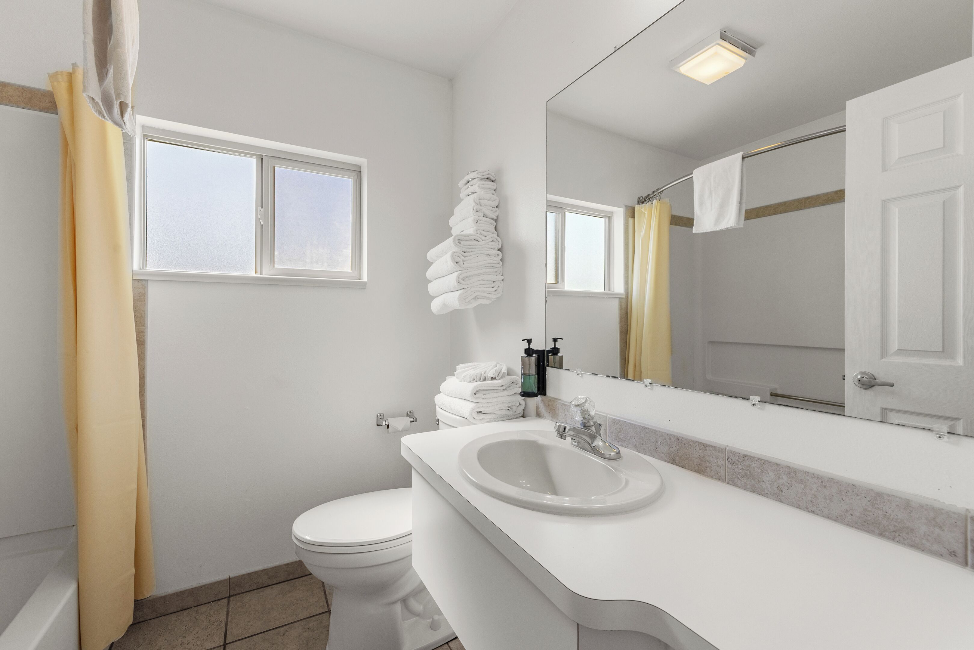 A modern bathroom with a toilet, sink, and a large mirror.