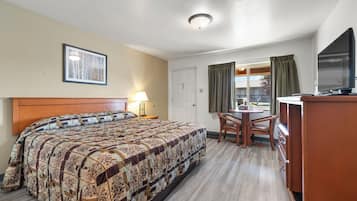 A hotel room with a bed, a desk, a chair, a television, and a window with curtains.