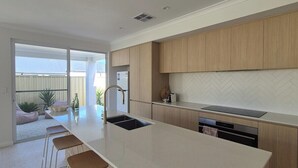 A modern kitchen with a central island, bar stools, and a view to the outside.
