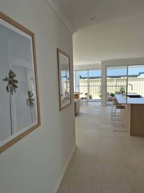 A spacious living area with a large window, a kitchen with bar stools, and framed artwork on the walls.