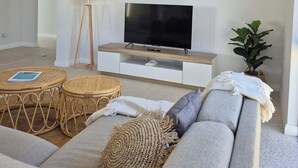 A modern living room with a flat-screen TV, a sofa, a coffee table, and a lamp.