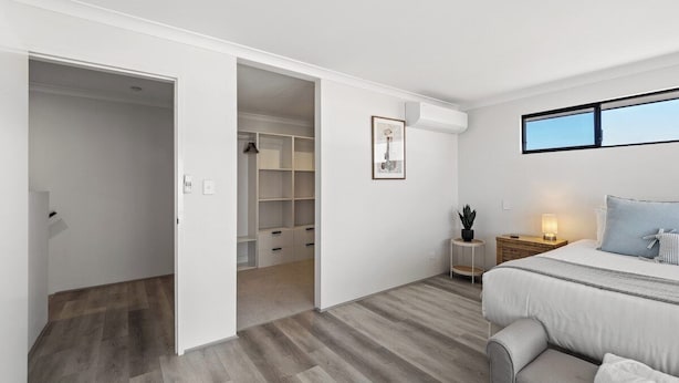 Een slaapkamer met een bed, nachtkastje en een raam.