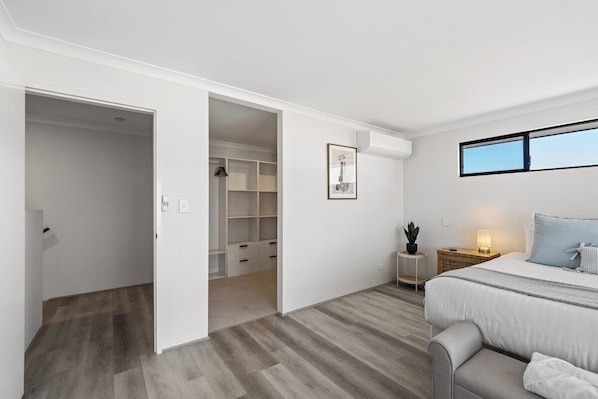 A bedroom with a bed, bedside table, and a window.