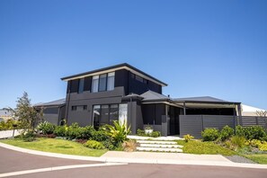 Une maison moderne à deux étages, dotée d’un garage, d’une allée couverte et d’un aménagement paysager bien entretenu.