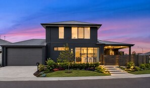 A modern two-story house with a garage, large windows, and a well-lit entrance.