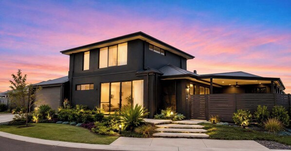 A modern two-story house with a garage, a well-maintained lawn, and a driveway.