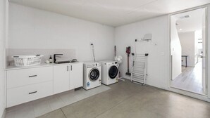 Een wasserette met een wasmachine, droger en een droogrek.