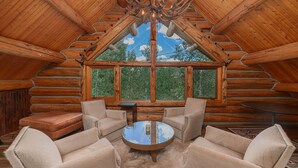 A log cabin interior with a large window, wooden ceiling beams, and a chandelier. - Absolutely Amazing Slopeside Mountain Lodge With spa (Telluride)