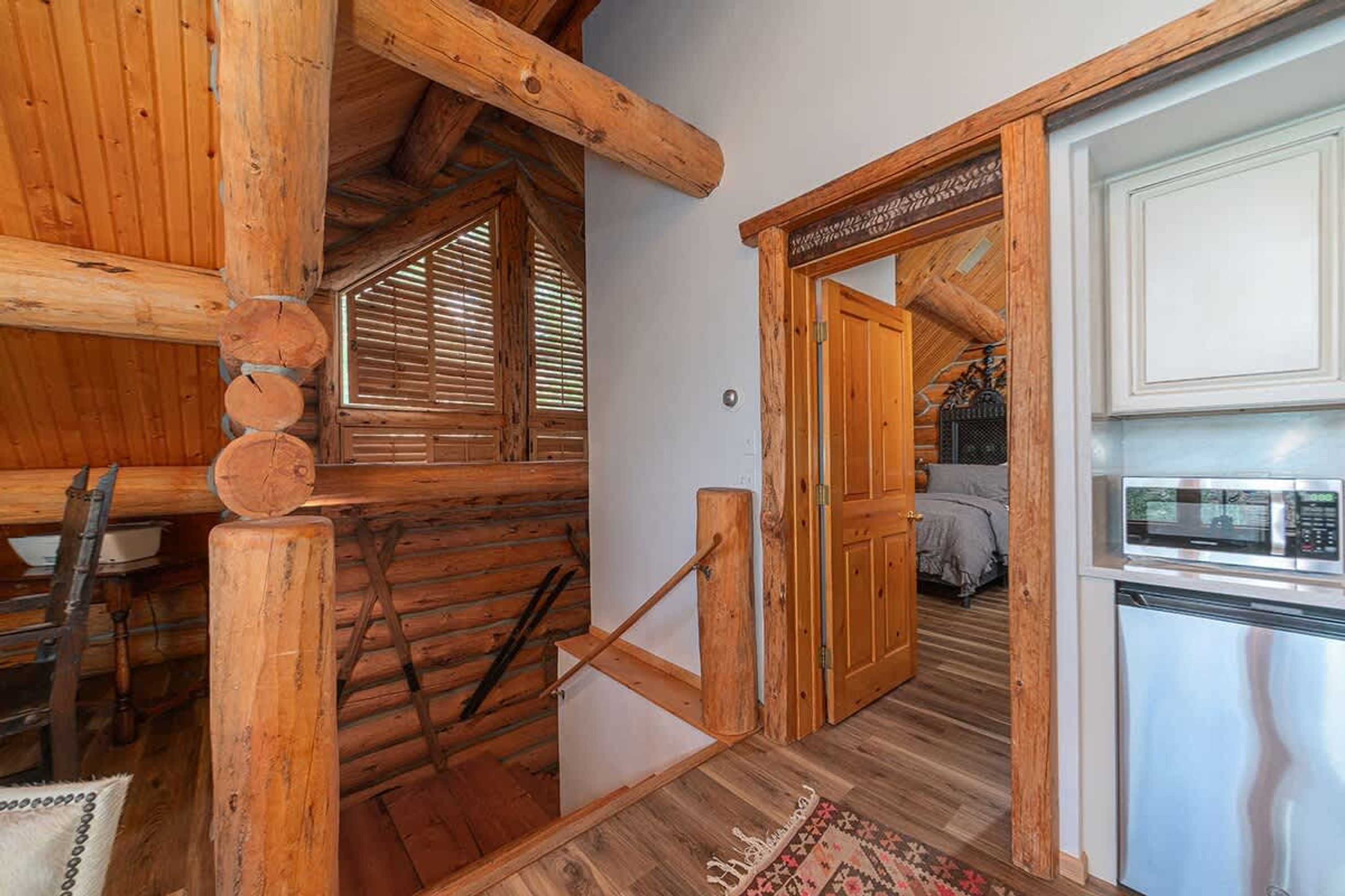 Un intérieur rustique en bois comprenant un coin cuisine, un espace repas et une chambre avec un lit et une fenêtre.