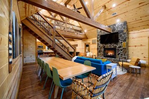 Cozy cabin interior with a dining area, seating area, and stone fireplace.