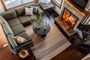 A cozy living room with a sectional sofa, a fireplace, and a coffee table with candles.