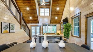 A spacious dining area with a long table, wooden walls, and a staircase leading to an upper level. - Family-friendly Broken Bow Cabin w spa Game Room (Broken Bow)