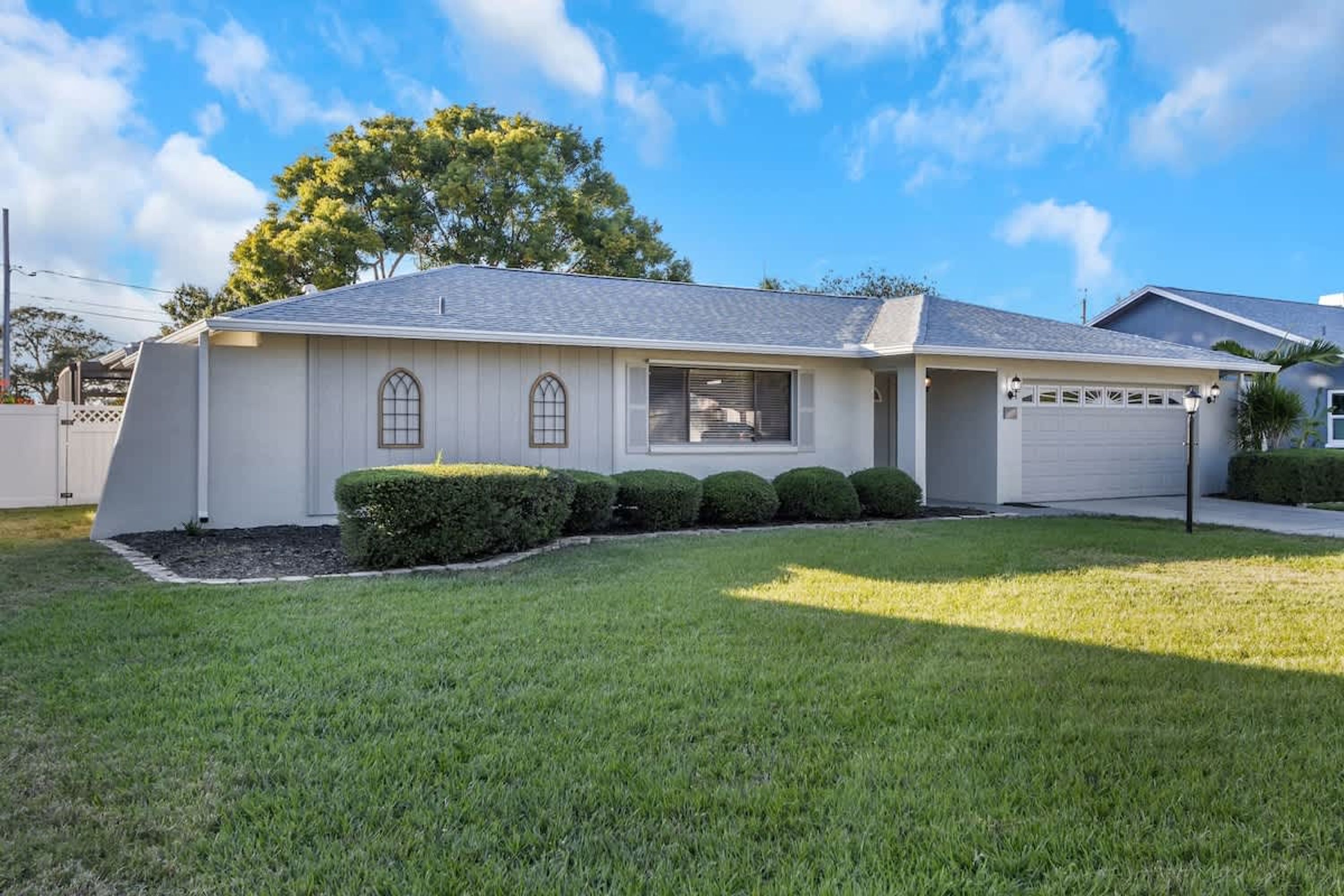 A single-story house with a garage, a covered porch, and a well-maintained lawn.