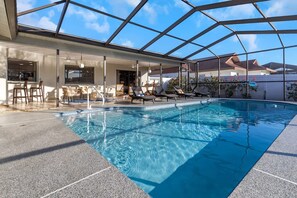 A swimming pool with lounge chairs and a glass-enclosed patio area. - Fun Family-friendly Modern Beach Home With Pool (Largo)
