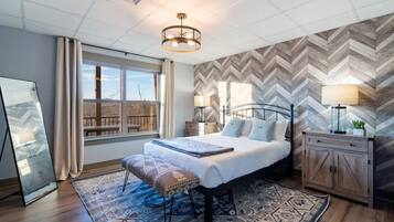 Relax in a spacious room with a large bed, matching bench, and a herringbone-patterned wall.