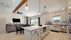 A modern kitchen with white cabinetry, a central island, and pendant lighting. - Secluded Hill Country Getaway Stunning Views Fire Pit 15 Min to Main Street 12 Guests (Fredericksburg)