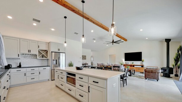 A spacious kitchen with white cabinetry, a central island, and pendant lighting. - Secluded Hill Country Getaway Stunning Views Fire Pit 15 Min to Main Street 12 Guests (Fredericksburg)