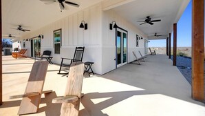 A covered outdoor area with ceiling fans, chairs, and tables. - Secluded Hill Country Getaway Stunning Views Fire Pit 15 Min to Main Street 12 Guests (Fredericksburg)