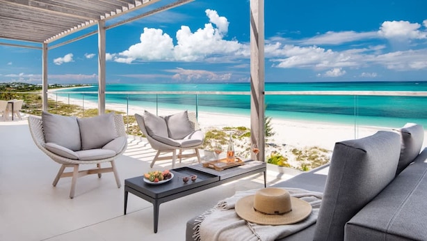 A covered outdoor seating area with a view of a beach and ocean. - Luxe Oceanfront Penthouse Hot Tub Daily Cabana (Providenciales)
