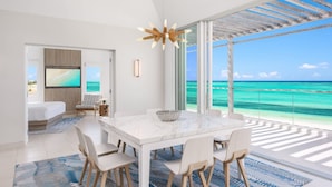 A modern hotel room with a large balcony, a dining area, and a TV. - Luxe Oceanfront Penthouse Hot Tub Daily Cabana (Providenciales)
