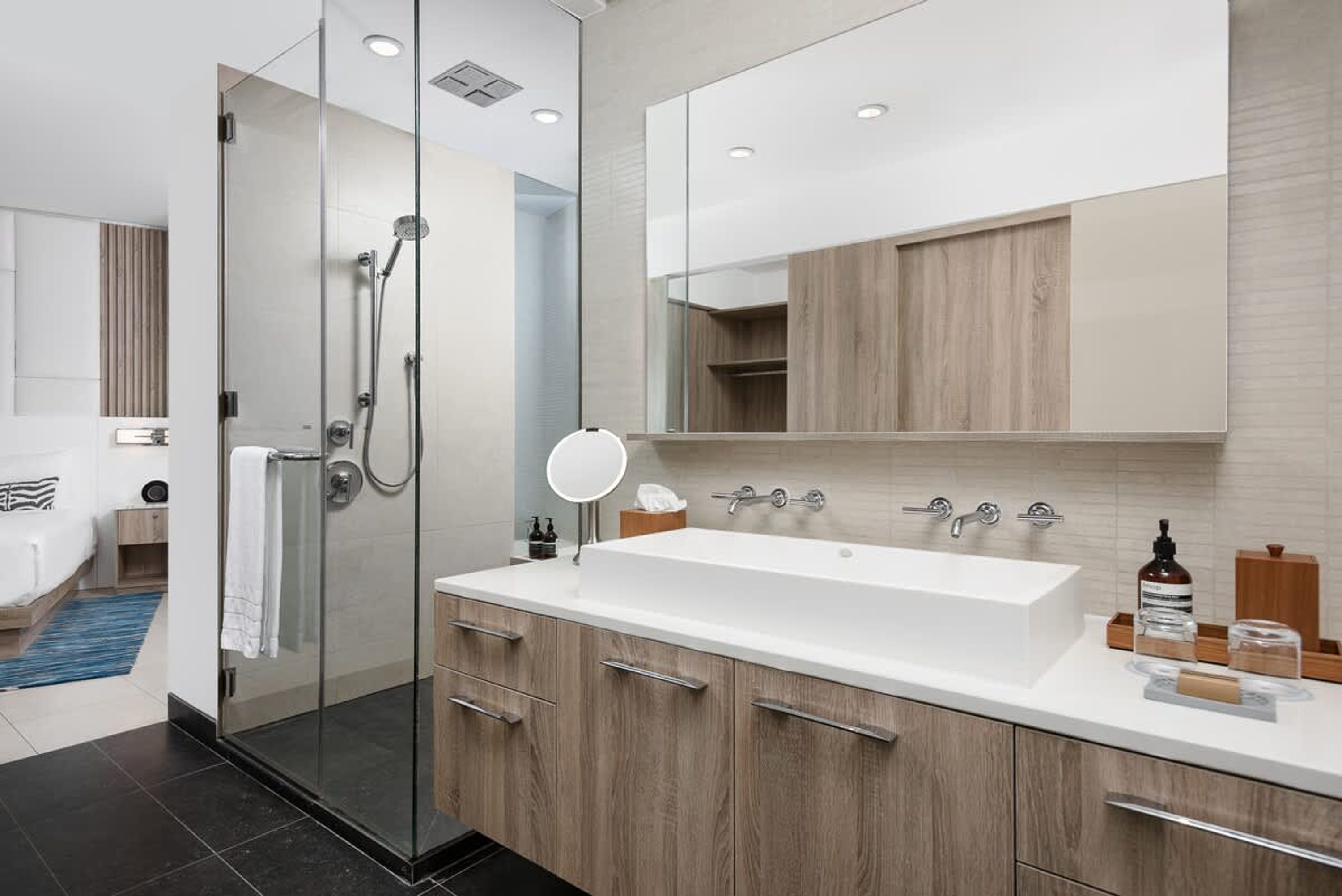 A modern bathroom with a glass-enclosed shower, a large white sink, and wooden cabinets.