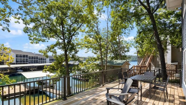 Une terrasse en bois avec des meubles d’extérieur, une vue sur un lac et un bâtiment doté d’une zone abritée.