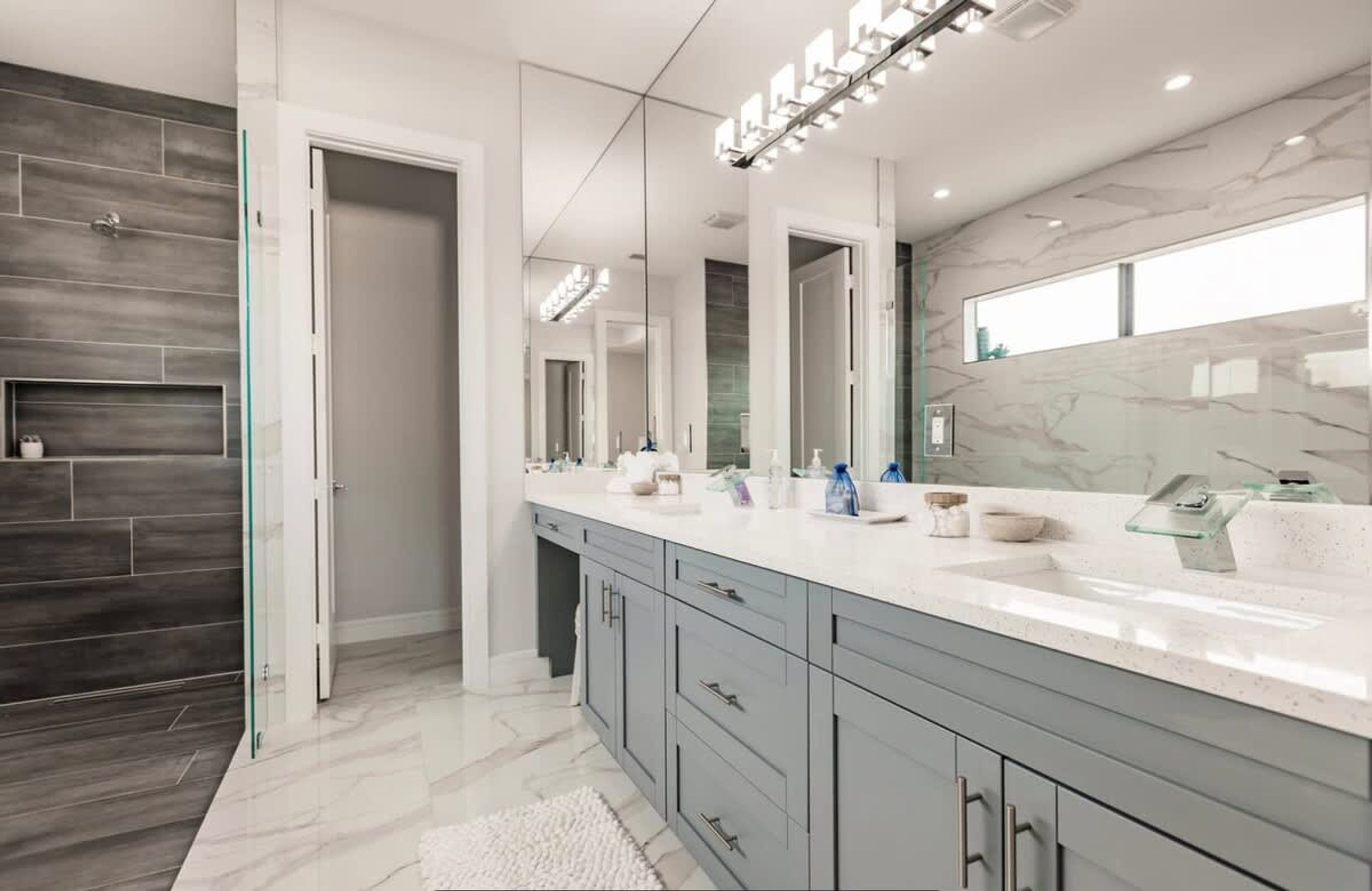 A modern bathroom with a large vanity, a mirror, and a shower area.
