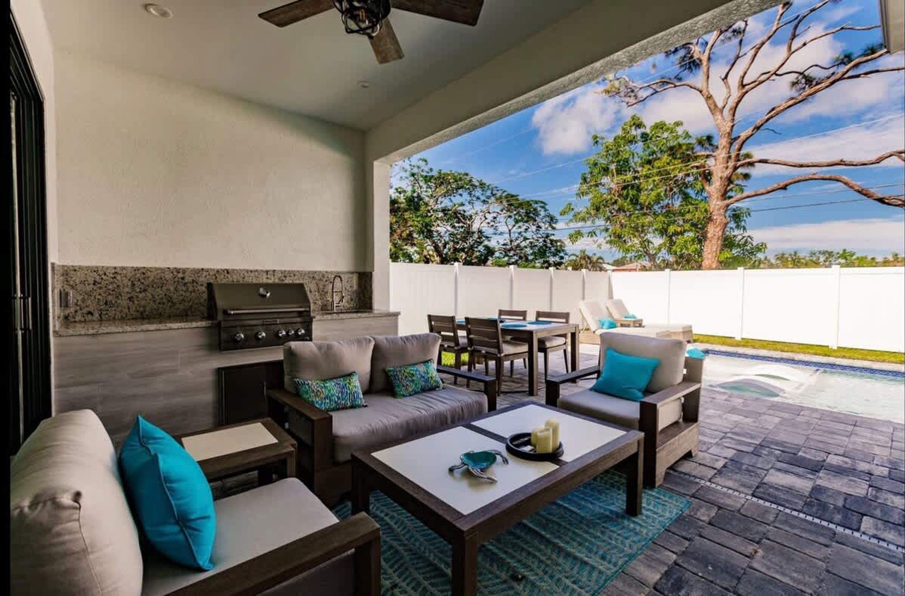 An outdoor patio area with a barbecue grill, seating, and a view of trees and sky.