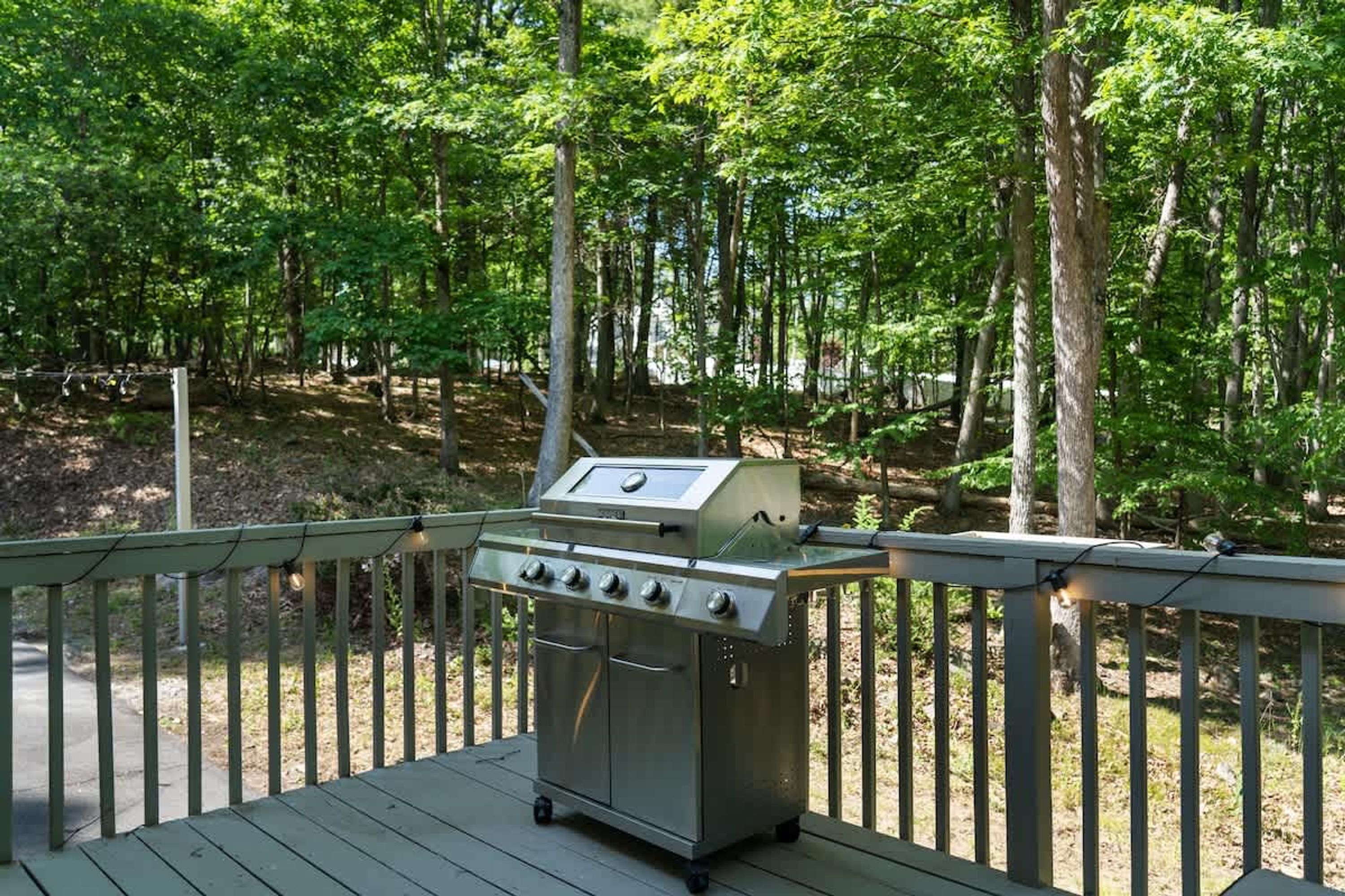 Una parrilla portátil sobre una terraza de madera rodeada de un bosque.