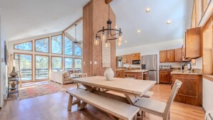 Una cocina amplia con armarios de madera, una gran mesa de comedor y una lámpara colgante.