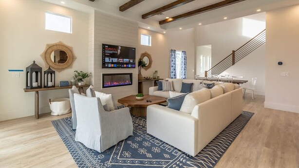 A spacious living room with a large sofa, a coffee table, and a fireplace. There is a staircase leading to another level, and a TV mounted on the wall. - Stunning Vanderbilt Beach House With Heated Pool (Naples)