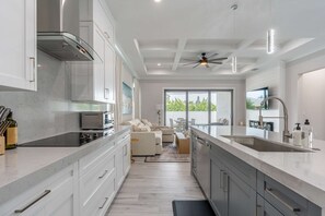 A modern kitchen with a large island, built-in appliances, and a view to the outdoors. - Sparkling new Vanderbilt Beach Luxury Escape (Naples)