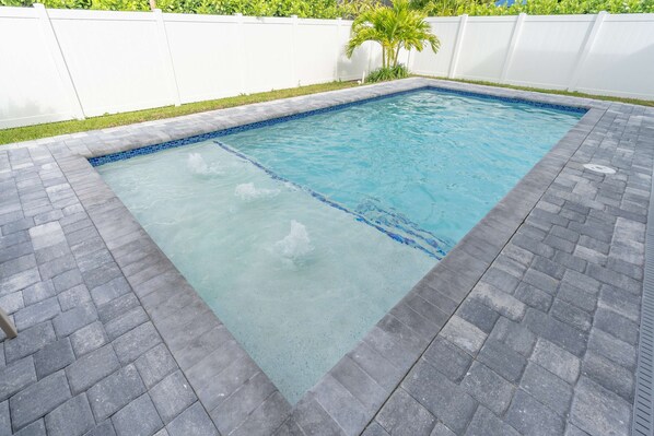 A rectangular swimming pool with a tiled edge, surrounded by a paved deck. - Sparkling new Vanderbilt Beach Luxury Escape (Naples)
