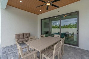 An outdoor patio with a wooden ceiling, a beige table, and a sofa. - Sparkling new Vanderbilt Beach Luxury Escape (Naples)