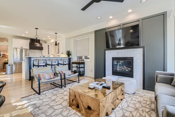 A modern living room with a fireplace, a dining area, and a kitchen. - Old Town Ski-in Out Hot Tub Walk to Main St (Park City)
