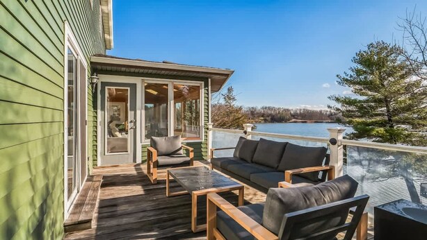 A wooden deck with outdoor furniture, a glass door leading to a covered area, and a view of a lake. - Billingswood by Boutiq (Athens)