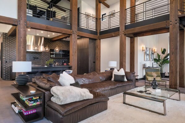 A spacious living area with a brown leather sofa, a glass coffee table, and a bookshelf. - Architecturally Stunning Cle Elum Luxury Retreat (Cle Elum)