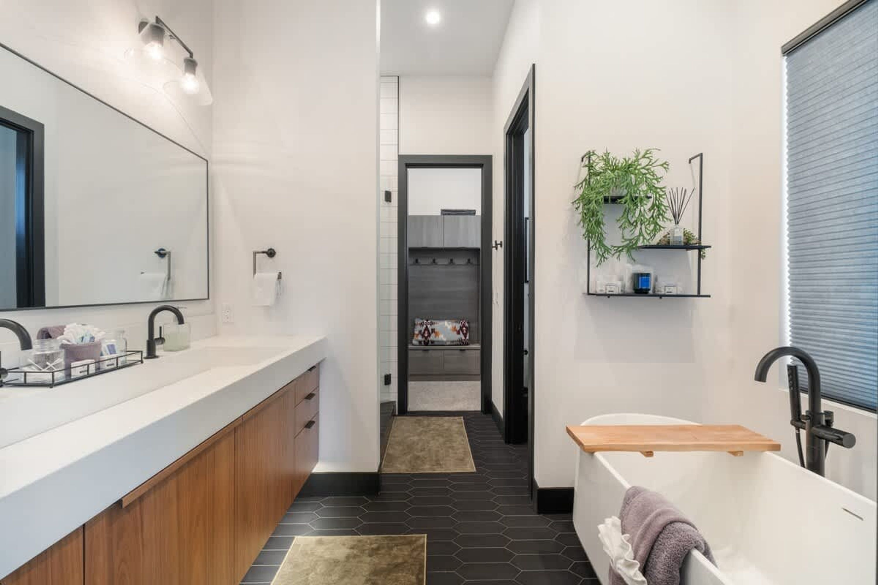 Une salle de bain moderne avec un grand miroir, un meuble-lavabo, une baignoire et un espace douche.