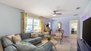 A modern living room with a grey sofa, wicker chairs, a coffee table, and a flat-screen TV. - Fun Family-friendly Largo Home Heated Pool (Largo)