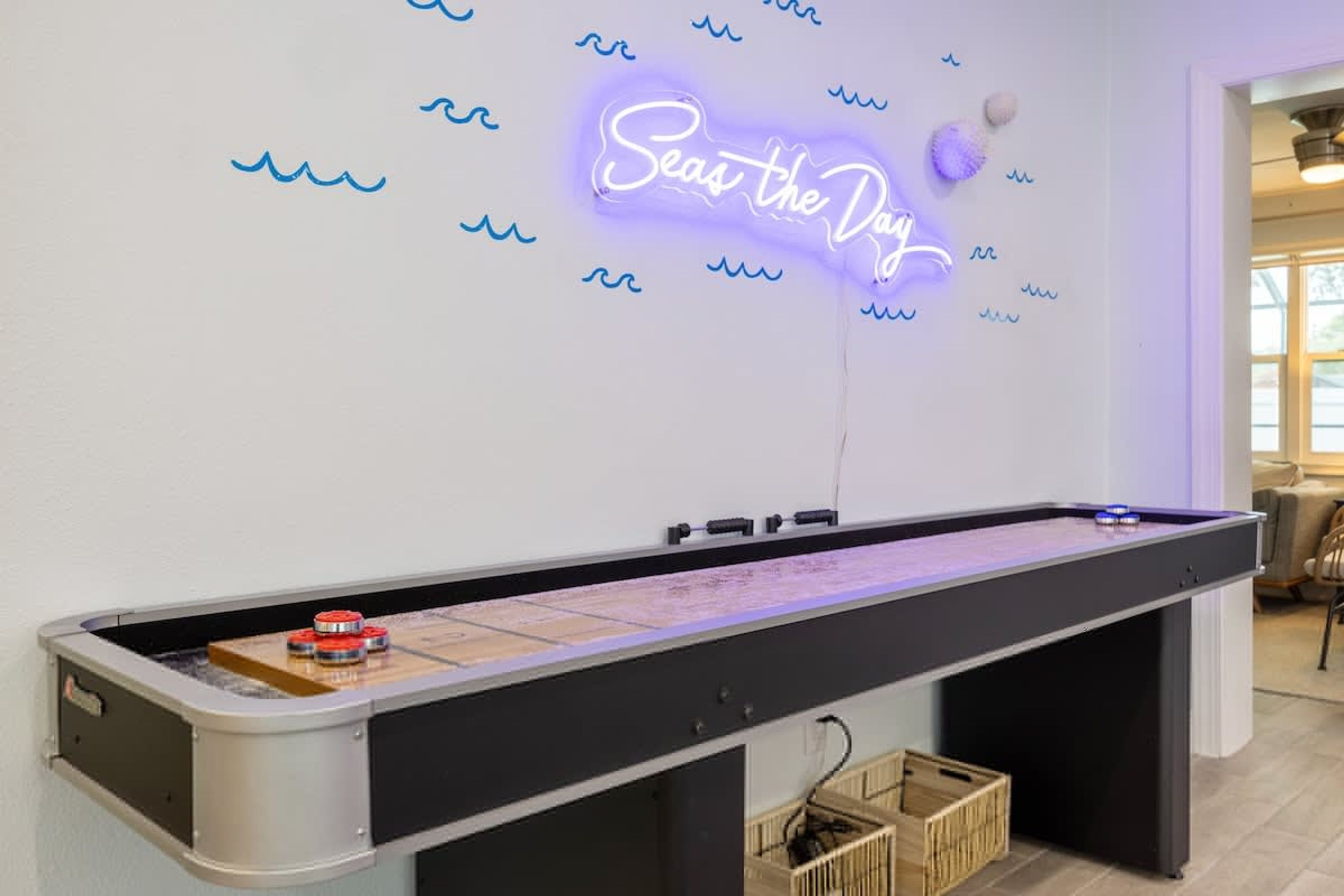 Ein Billardtisch mit einem Neon-Schild, das "Seas the Day" zeigt, in einem Raum mit schlichtem, klarem Design.