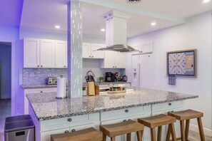 A modern kitchen with white cabinets, a granite countertop, and a central island with bar stools. - Fun Family-friendly Largo Home Heated Pool (Largo)
