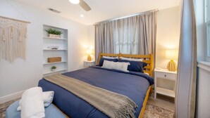 A bedroom with a bed, bedside tables, a ceiling fan, and a window with curtains. - Fun Family-friendly Largo Home Heated Pool (Largo)