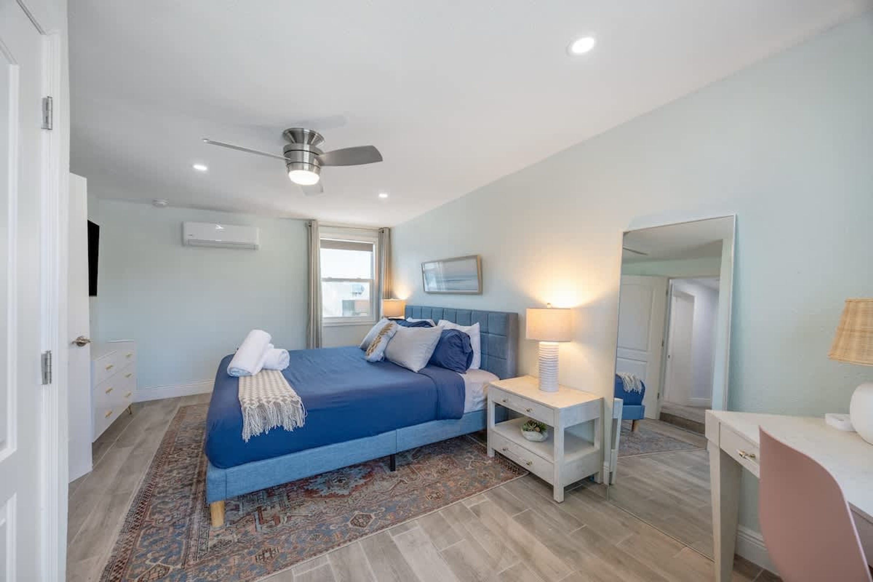 A bedroom with a bed, bedside tables, a ceiling fan, and a window.