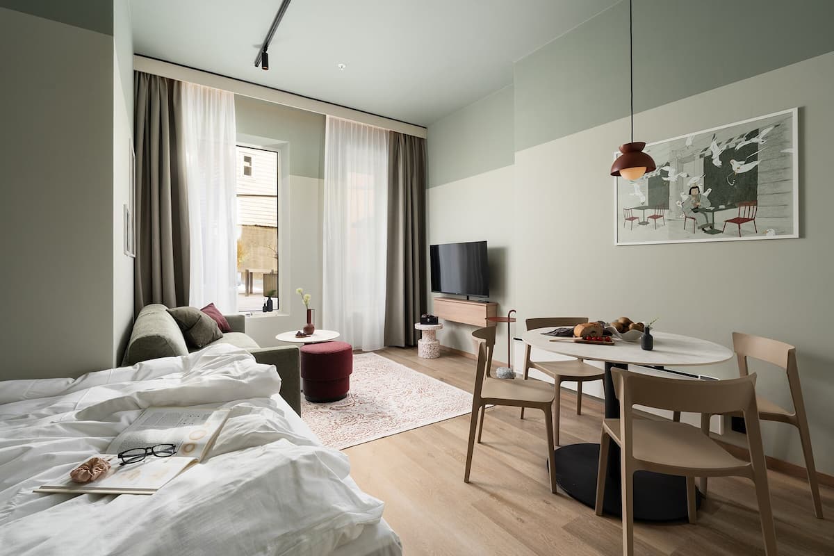 Ett modernt hotellrum med en säng, ett skrivbord, ett matbord och en TV.